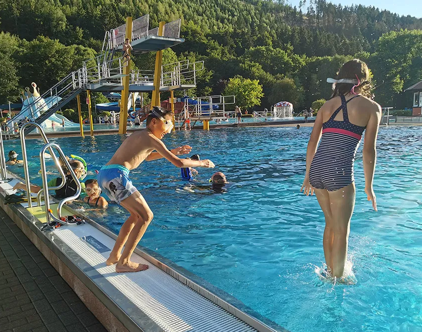 Zwei Kinder springen vom Rand ins Wasser