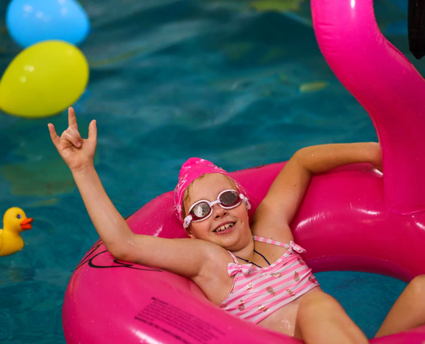 Mädchen sitzt in einem aufblasbaren Flamingo im Pool